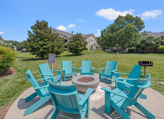A set of blue chairs are arranged around a fire pit.