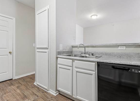 A kitchen with a white cabinet and a black dishwasher.