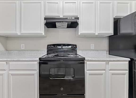 A kitchen with black appliances and white cabinets.