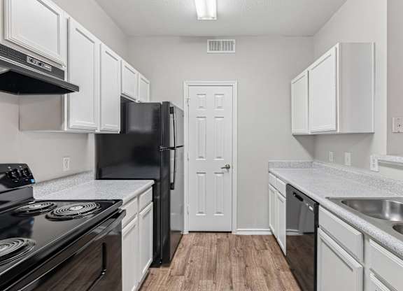 A kitchen with black appliances and white cabinets.