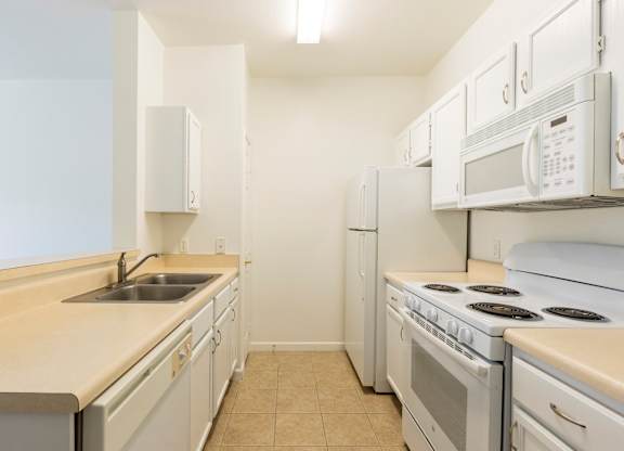 A kitchen with white appliances and a beige countertop.