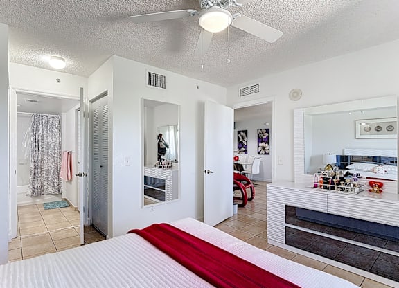 A bedroom with a bed in the center and a red blanket on it.