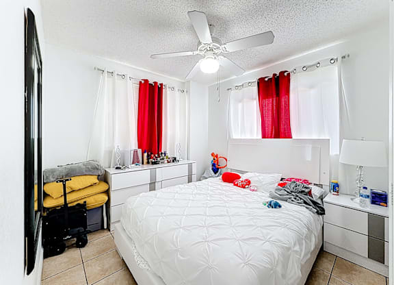 A bedroom with a white bed and a ceiling fan.
