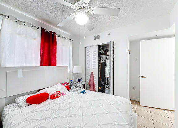 A bedroom with a white bed and a ceiling fan.