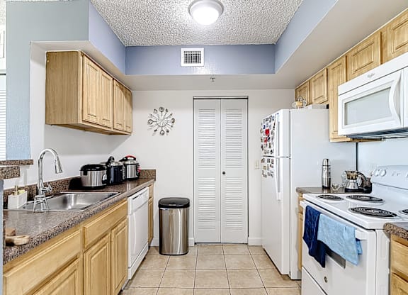 A kitchen with white appliances and wooden cabinets.