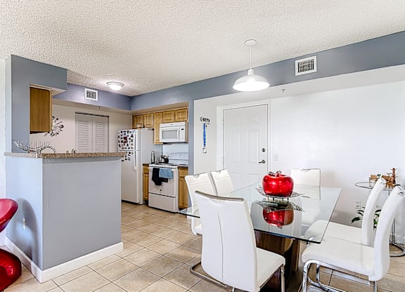 A kitchen with a table and chairs in the foreground and a refrigerator in the background.