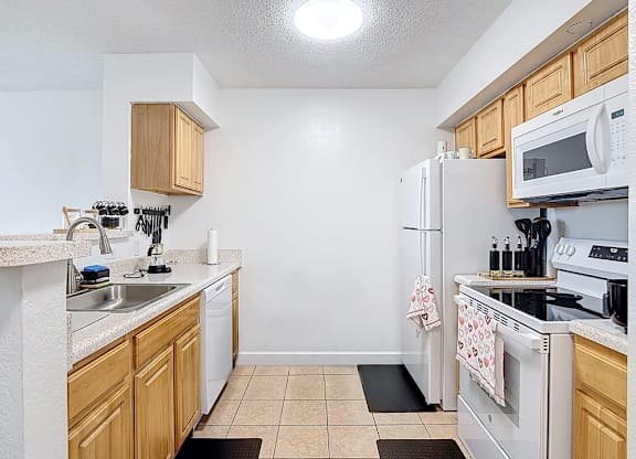 A kitchen with white appliances and wooden cabinets.