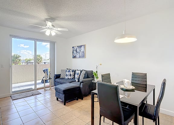 A living room with a sliding glass door and a dining table with chairs.
