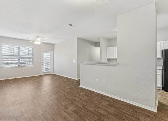 A spacious living room with hardwood floors and white walls.