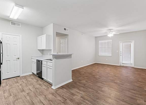 A kitchen with white cabinets and a wooden floor.