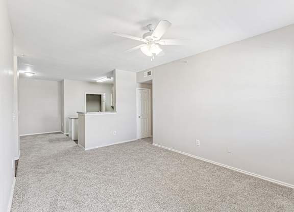 A spacious room with a ceiling fan and carpeted floor.