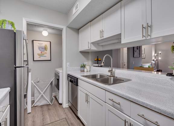 A kitchen with white cabinets and a grey refrigerator.