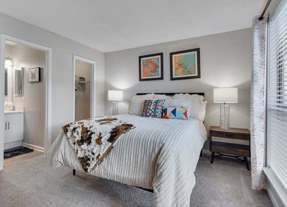 A bedroom with a large bed and two lamps.