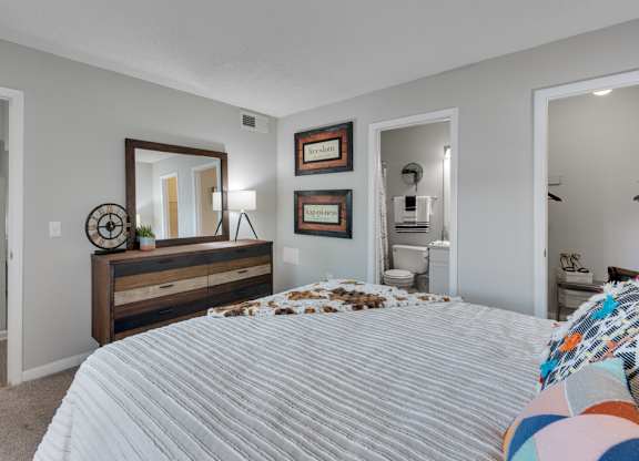 A bedroom with a large bed and a dresser with a mirror above it.