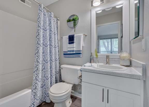 A white bathroom with a toilet, sink, and shower.