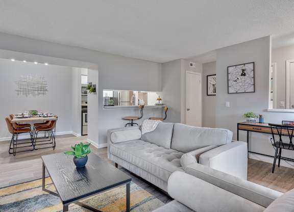A modern living room with a white couch and a glass coffee table.