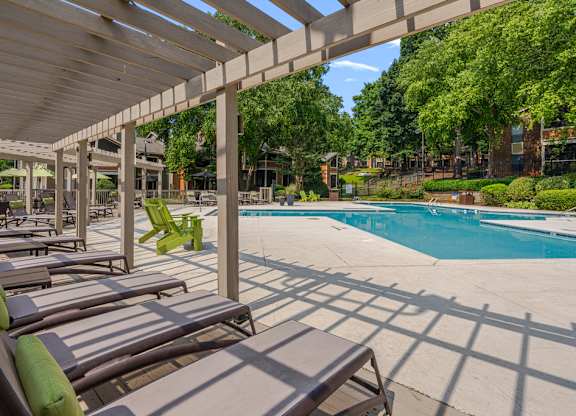 A pool area with sun loungers and a wooden pergola.