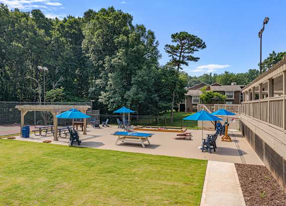 A sunny day at the park with blue umbrellas and benches.