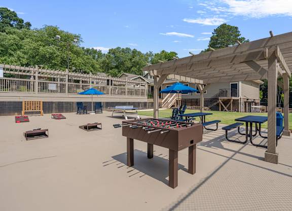 A playground with a shaded picnic table and a swing set.