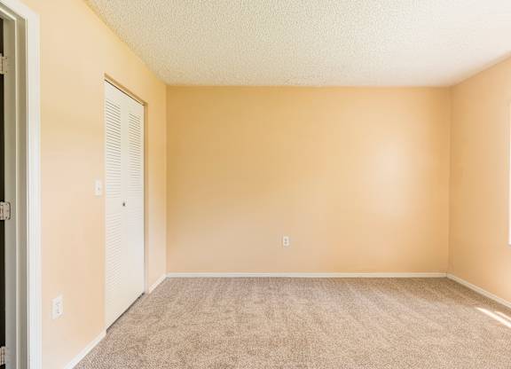 A room with beige walls and carpeted floor.
