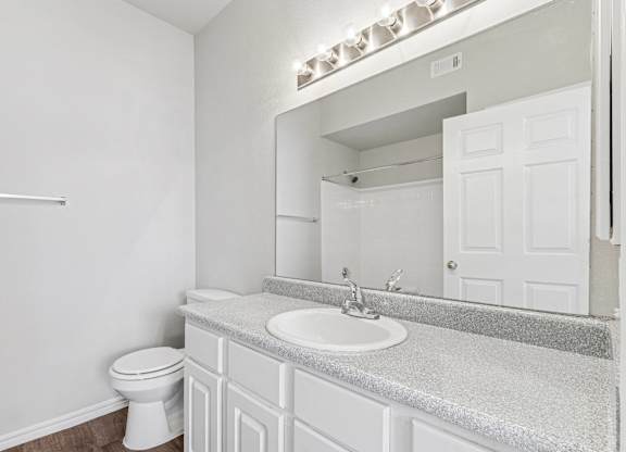 A white bathroom with a toilet, sink, and mirror.