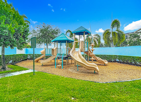 A playground with a blue and yellow slide and a green roofed structure.