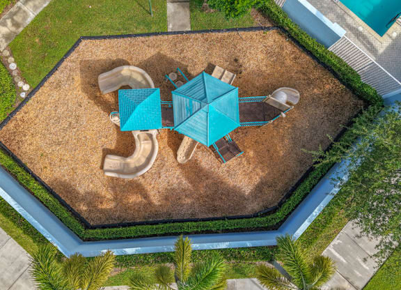 A playground with a blue umbrella and a brown sandbox.