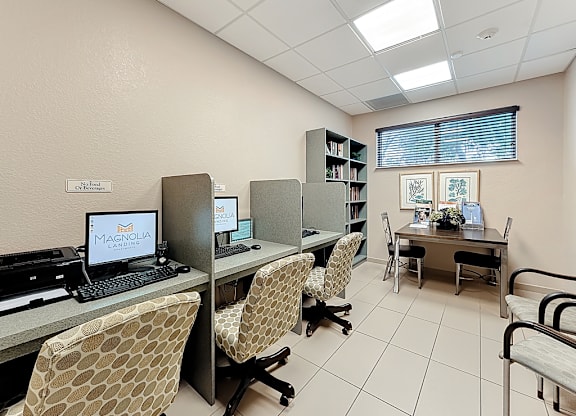A room with a desk, chairs, and computers.