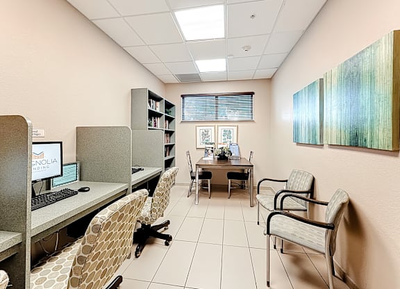 A room with a desk, chairs, and a computer.