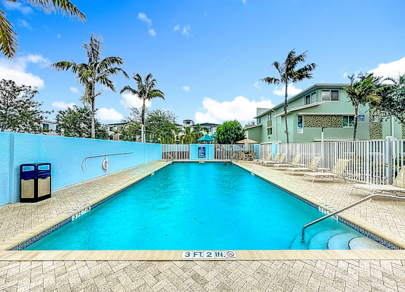 A swimming pool with a blue tiled wall and a diving board.