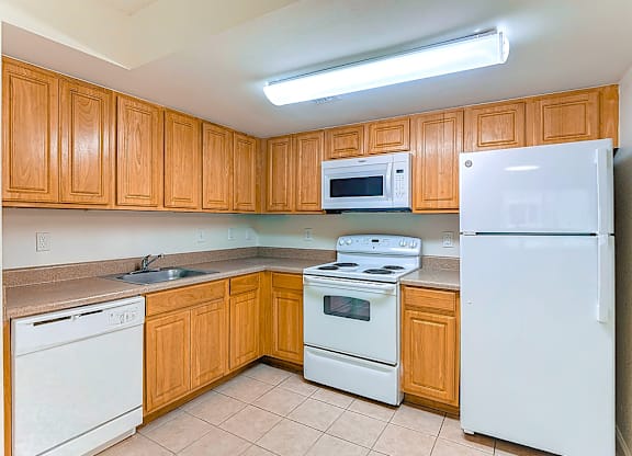 A kitchen with white appliances and wooden cabinets.