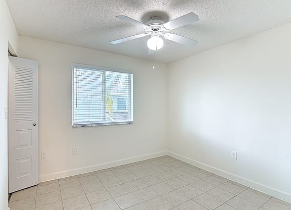 A room with a ceiling fan and a window with blinds.
