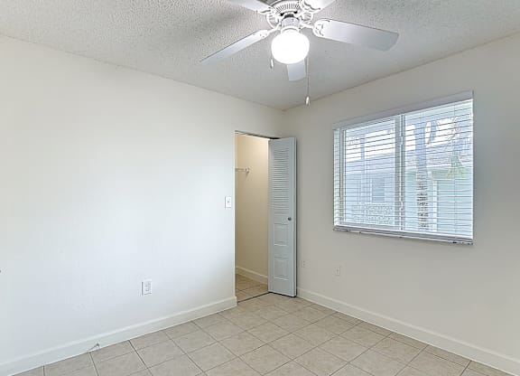 A room with a ceiling fan and a door leading to another room.