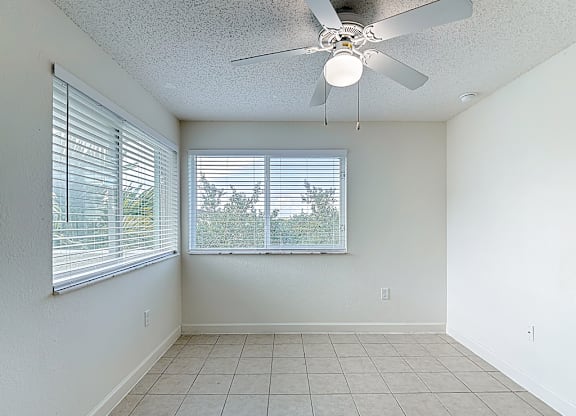 A room with a ceiling fan and a window with blinds.