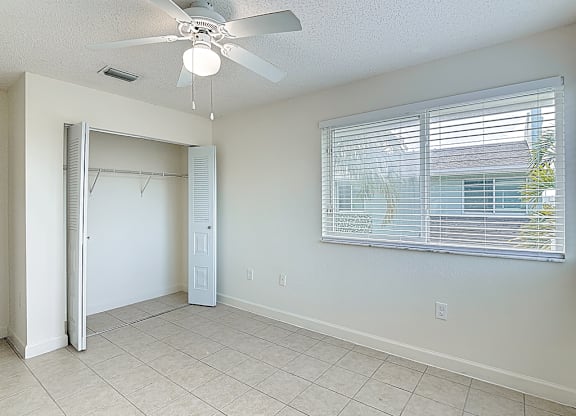 A room with a ceiling fan and a window with blinds.
