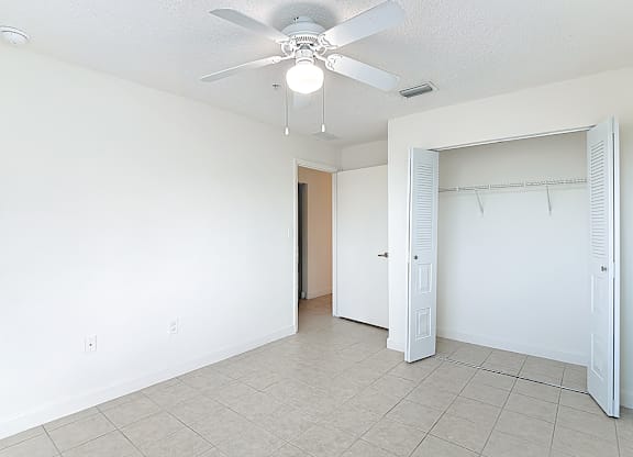 A room with a ceiling fan and a doorway leading to another room.