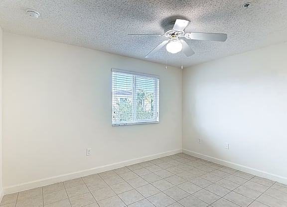 A room with a ceiling fan and a window with blinds.