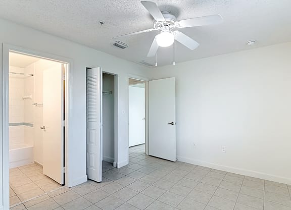 A white room with a ceiling fan and tile flooring.