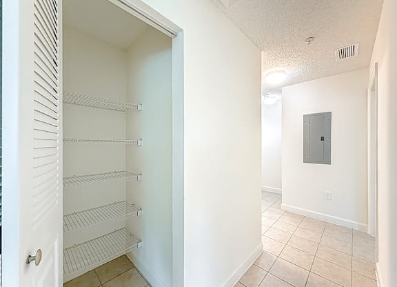 A white pantry with a door open to a hallway.