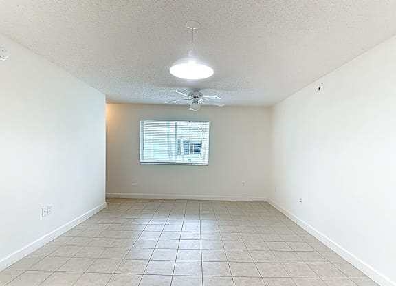 Empty room with a ceiling fan and a window.