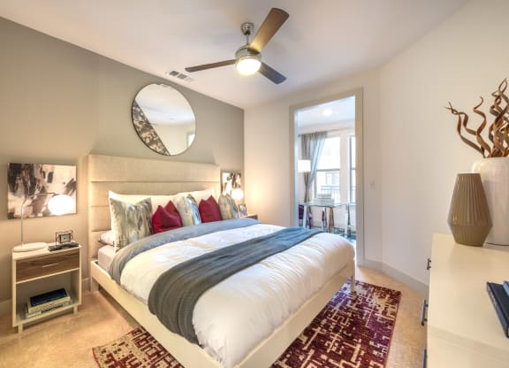Bedroom with wood flooring and a bed facing the entry doorway into the apartment.