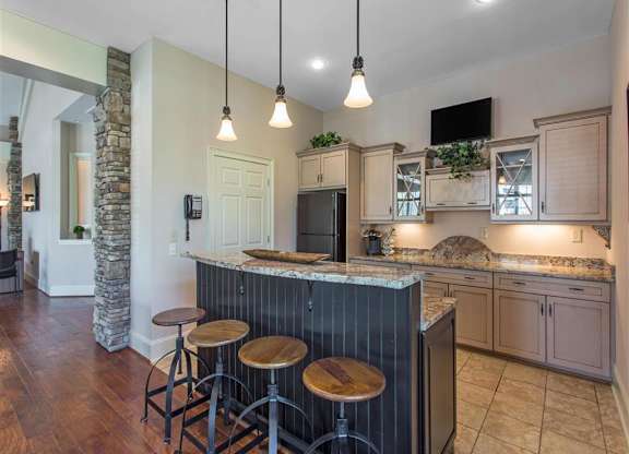 Clubhouse Kitchen with Tan Counters Black Appliances and Wood and Metal Stools at Breakfast Bar