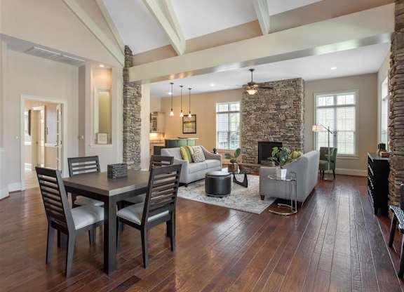 Clubhouse Seating Area with Dining Room Table with Chairs  Grey Couches Triangle Glass Coffee Table Brick Fireplace with Windows and Decorations