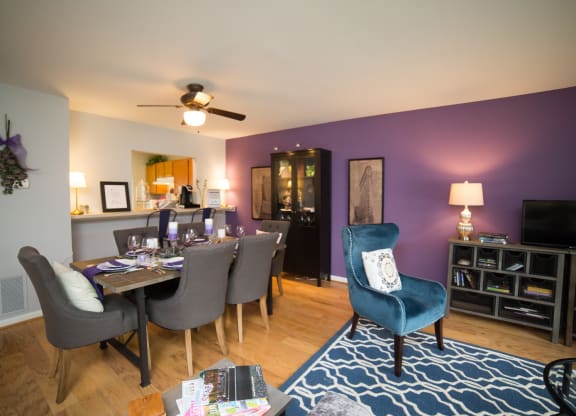 Dining room table with ceiling fan above the table . Living room is next to the dinning room