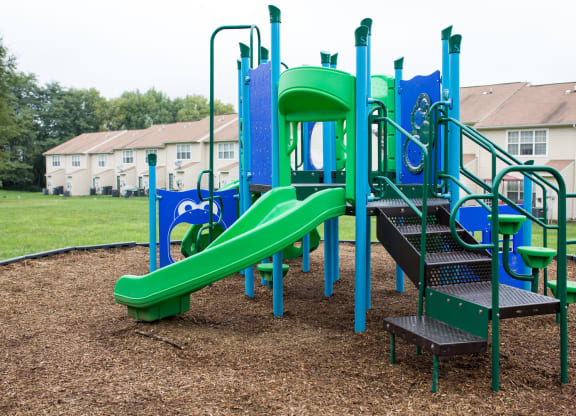 Playground with wood chips in court yard between buildings.