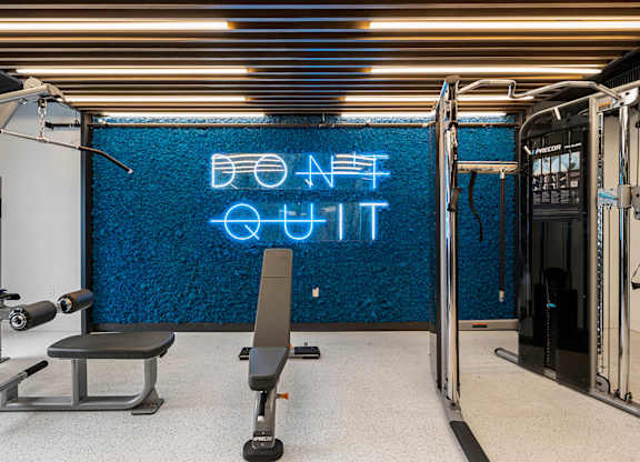 a gym with a blue neon sign on the wall and a gym chair