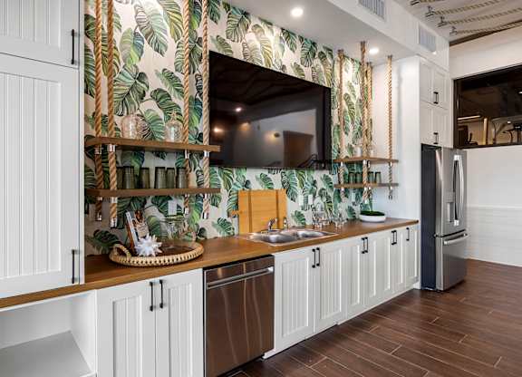 a kitchen with white cabinets and a sink and a television