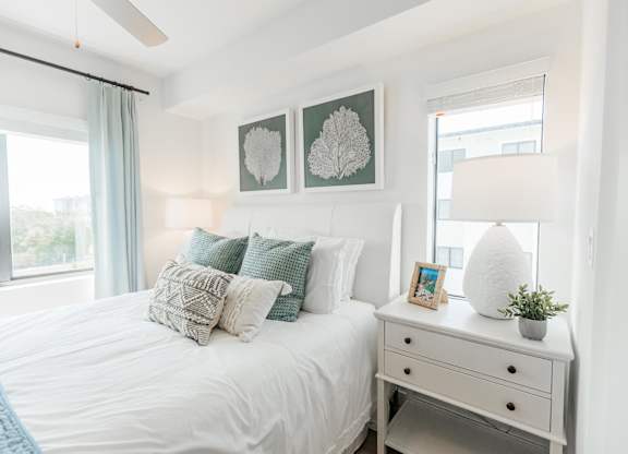 a bedroom with a bed with pillows and a dresser with a lamp and