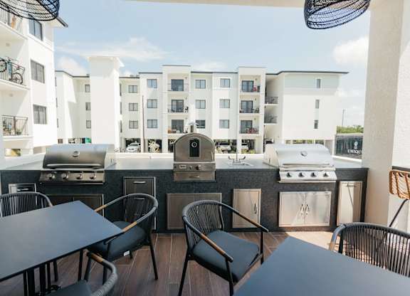 a patio with a grill and tables with chairs