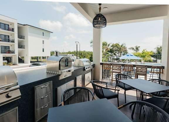 a covered patio with tables and chairs and barbecue grills